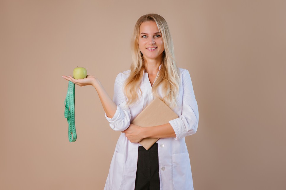 nutritionist doctor holds a centimeter ribbon on a light background, space for text. the concept of losing weight and eating healthy.